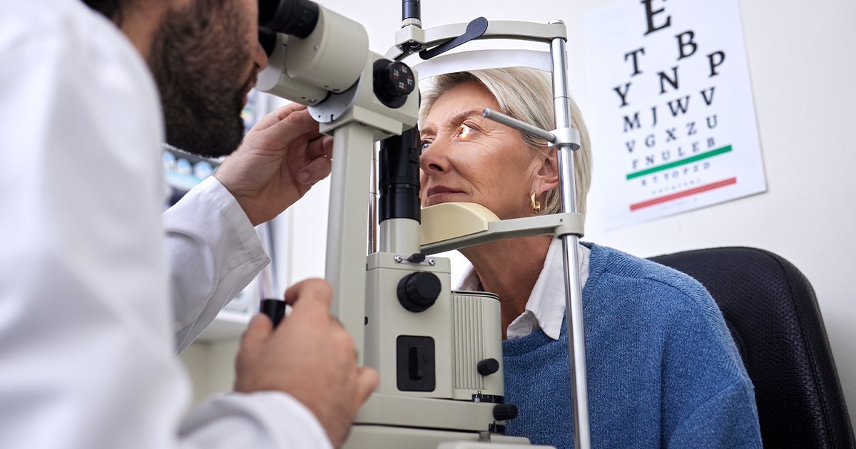 A woman is engaged in an eye exam, looking closely at the eye chart for testing her vision.